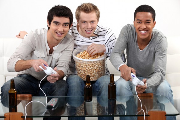 Three friends playing video games while drinking beer.