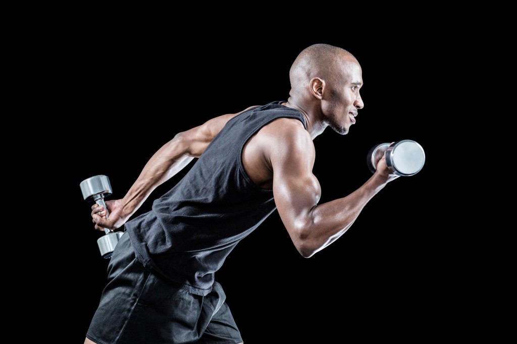 Side view of muscular man running while holding dumbbell