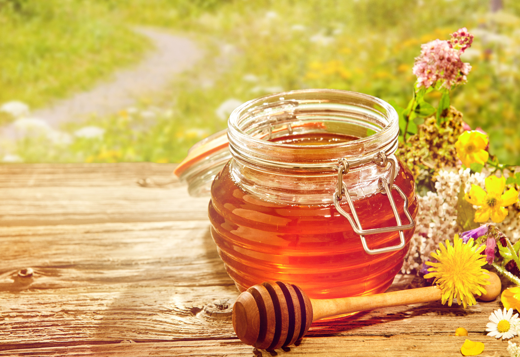Jar of honey with dipper with flowers